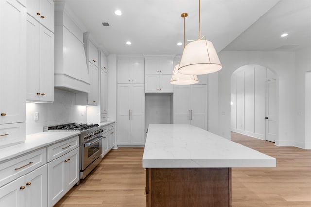 2050 Osprey Poynte, Greensboro, GA 30642 - kitchen featuring high end stove, premium range hood, recessed lighting, light wood-type flooring, and a kitchen island