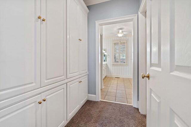 corridor featuring baseboards, light carpet, light tile patterned flooring, and ornamental molding