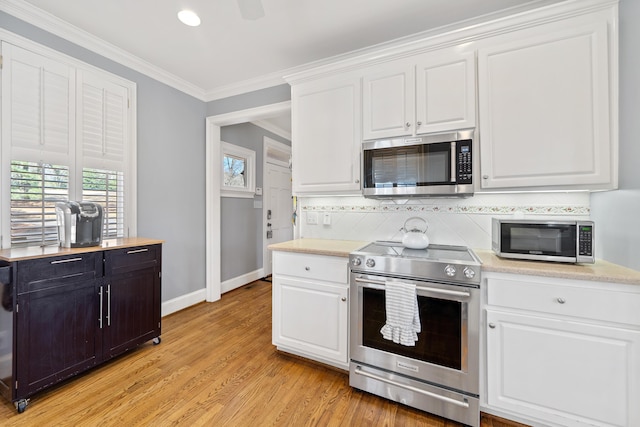 kitchen featuring backsplash, light countertops, ornamental molding, white cabinets, and stainless steel appliances