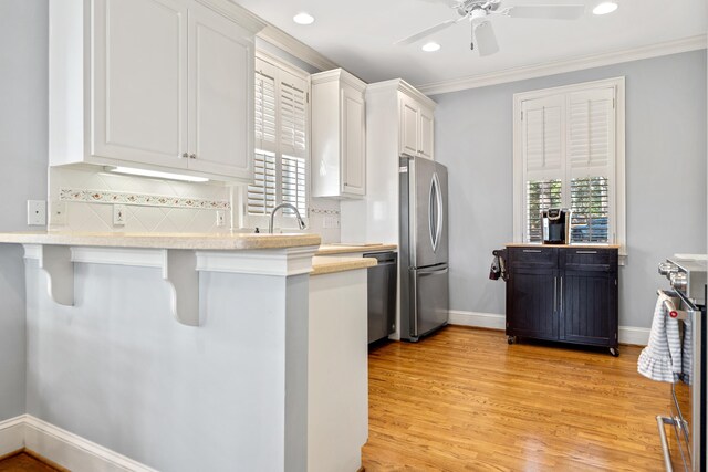 kitchen featuring light wood finished floors, white cabinets, stainless steel appliances, and light countertops