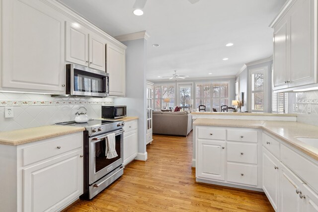 kitchen with light wood finished floors, crown molding, light countertops, appliances with stainless steel finishes, and white cabinets