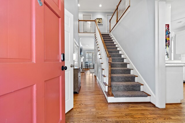 entryway with stairway, baseboards, wood finished floors, and crown molding