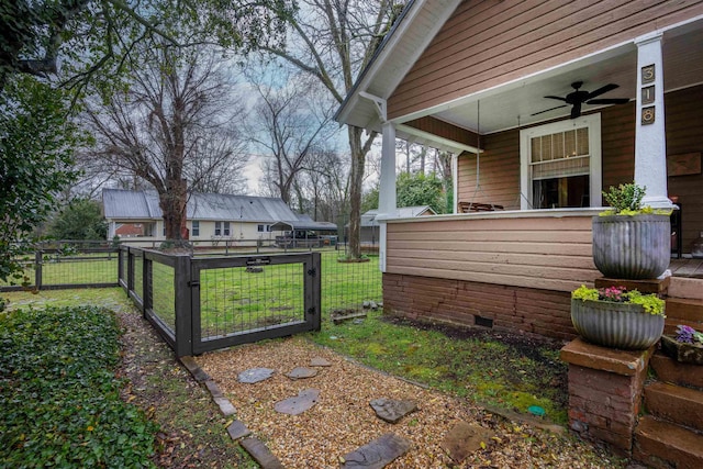 view of yard with a gate, fence, and ceiling fan