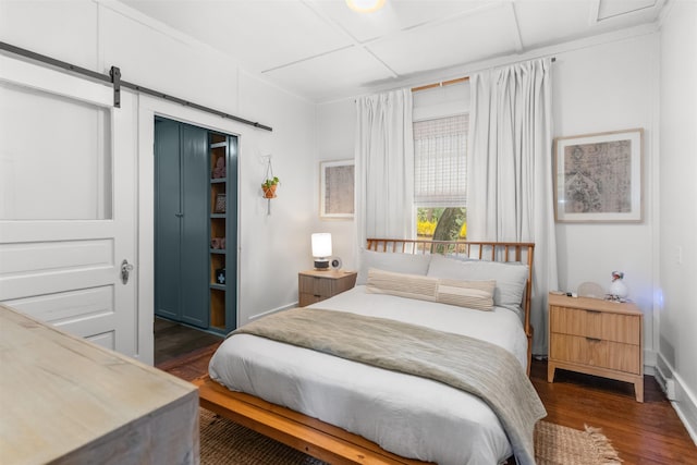 bedroom with a barn door, baseboards, a closet, and dark wood-style flooring