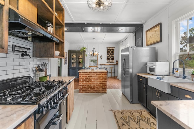 kitchen with open shelves, a sink, under cabinet range hood, appliances with stainless steel finishes, and a chandelier