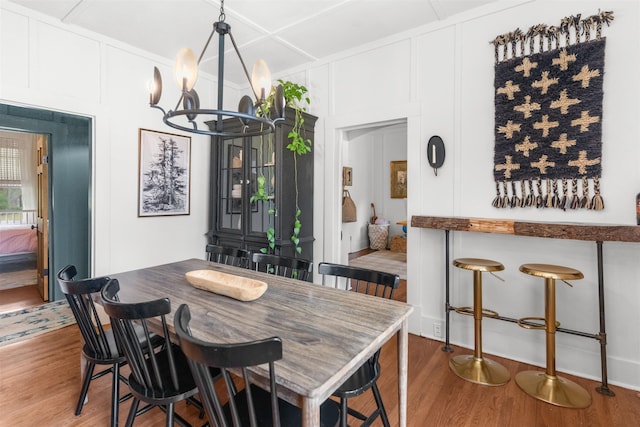 dining room featuring a chandelier, wood finished floors, and a decorative wall