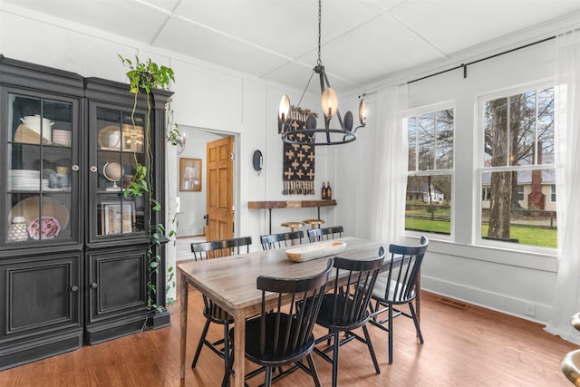 dining area featuring a notable chandelier, visible vents, baseboards, and wood finished floors