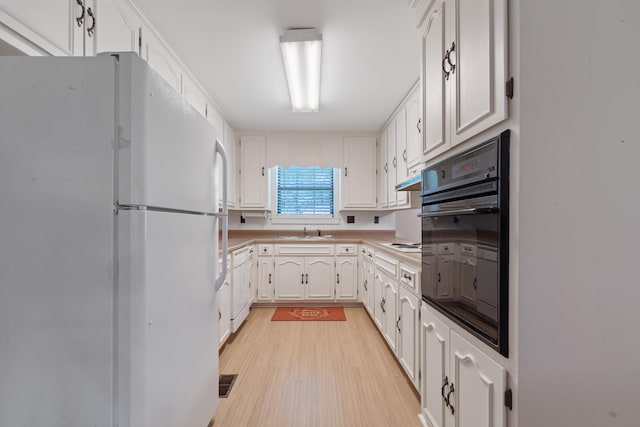 kitchen with a sink, white appliances, light countertops, white cabinetry, and light wood-type flooring