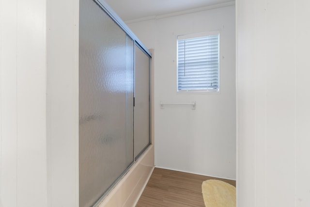 bathroom featuring crown molding, wood finished floors, and shower / bath combination with glass door
