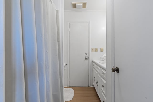 bathroom with crown molding, visible vents, wood finished floors, and vanity