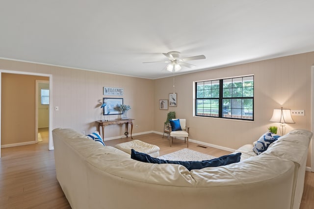 living room featuring baseboards, ceiling fan, wood finished floors, and a wealth of natural light