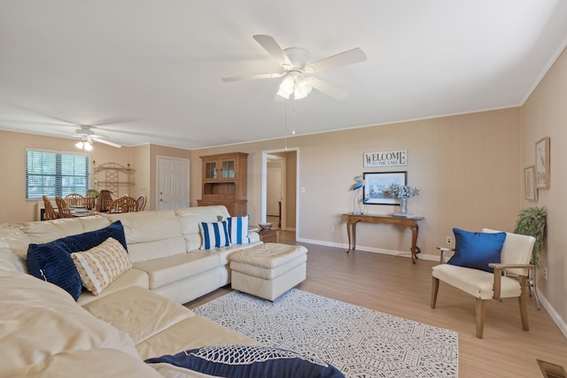 living room with light wood-type flooring, baseboards, ceiling fan, and visible vents