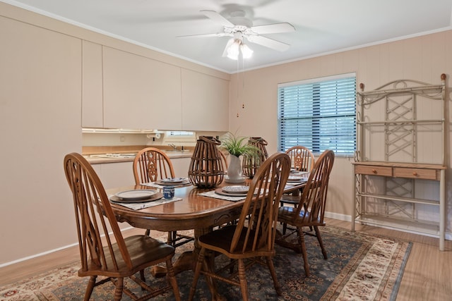 dining space featuring light wood-style floors, ornamental molding, baseboards, and ceiling fan