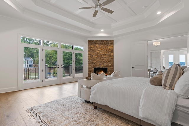 bedroom with multiple windows, light wood-type flooring, access to exterior, and a fireplace