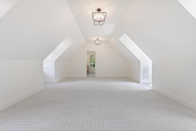 additional living space with a chandelier, vaulted ceiling, and light carpet