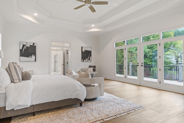 bedroom featuring a raised ceiling, ensuite bathroom, access to outside, and light hardwood / wood-style floors