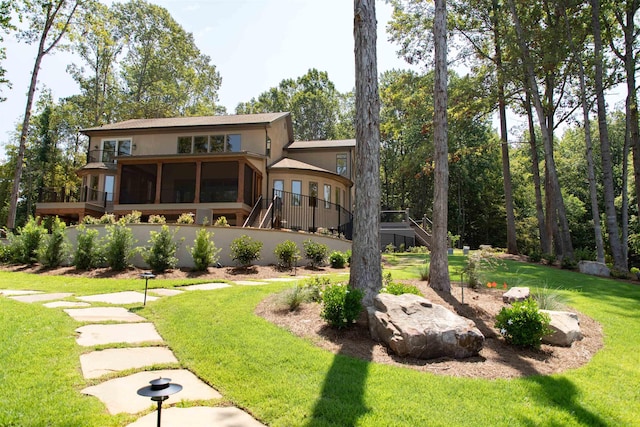 back of house featuring a sunroom and a lawn