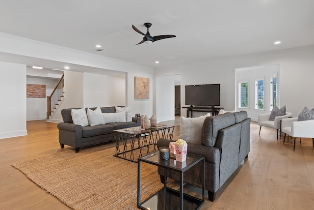 living room with ceiling fan, ornamental molding, and light wood-type flooring