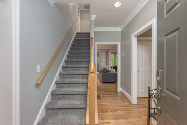 stairway with hardwood / wood-style flooring and ornamental molding