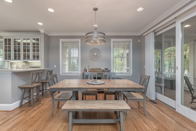 dining space featuring an inviting chandelier, ornamental molding, and light wood-type flooring
