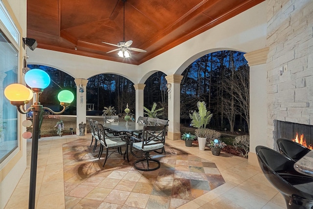 view of patio featuring outdoor dining space, ceiling fan, and an outdoor stone fireplace