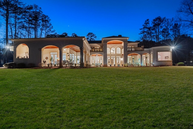 view of front of property featuring a front yard, a balcony, french doors, and stucco siding