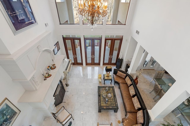 entrance foyer featuring visible vents, a chandelier, french doors, a towering ceiling, and a decorative wall