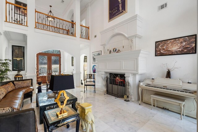 living area with visible vents, a lit fireplace, french doors, arched walkways, and marble finish floor