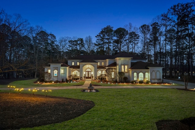 mediterranean / spanish-style home featuring curved driveway, a front yard, and stucco siding