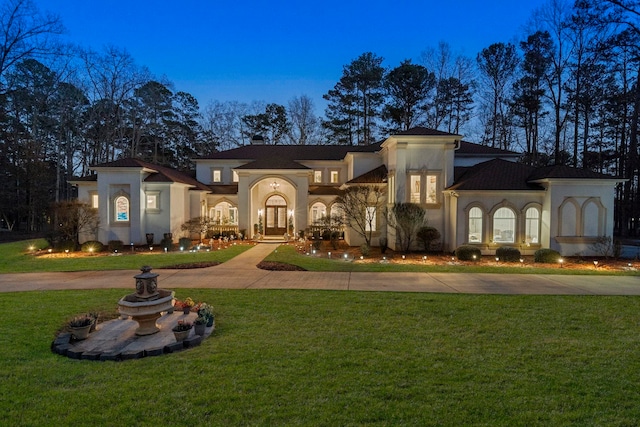 view of front facade featuring stucco siding, french doors, decorative driveway, and a front lawn