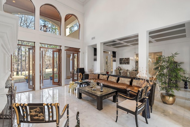 interior space with a chandelier, visible vents, coffered ceiling, and a high ceiling