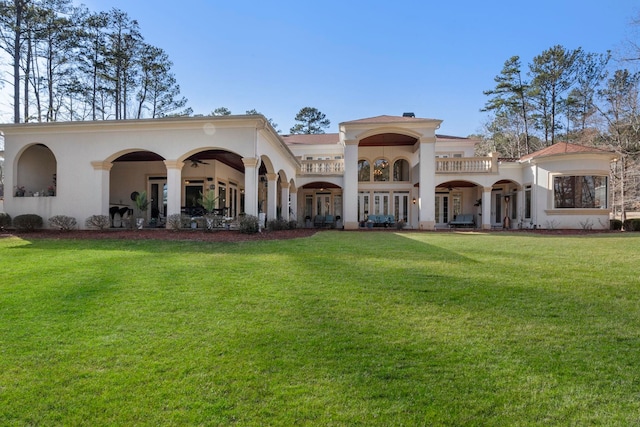 back of house featuring stucco siding and a lawn