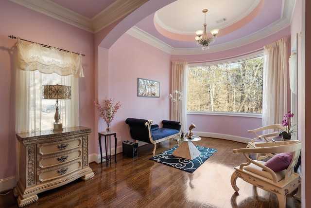 living area featuring wood finished floors, an inviting chandelier, arched walkways, ornamental molding, and a raised ceiling