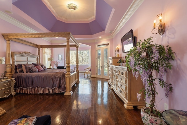 bedroom with dark wood finished floors, a tray ceiling, crown molding, and ornate columns