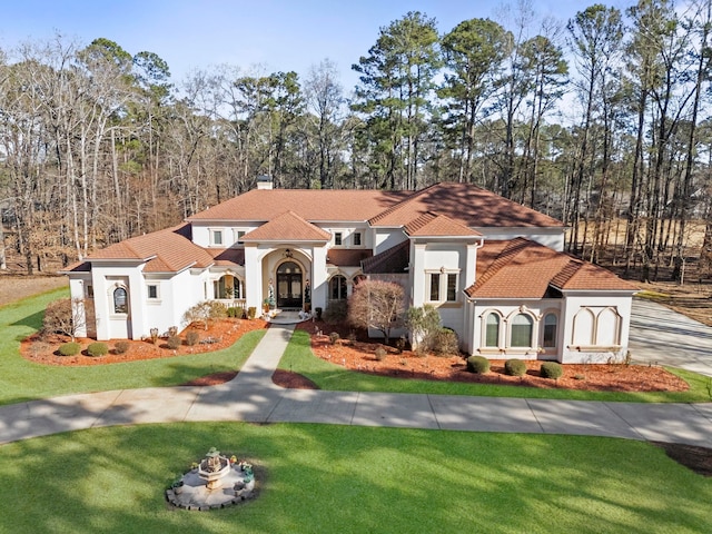 mediterranean / spanish home with a front yard, concrete driveway, and stucco siding