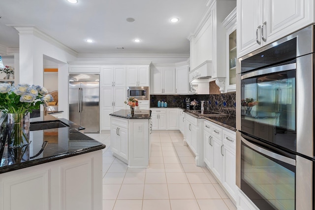 kitchen featuring glass insert cabinets, white cabinets, light tile patterned floors, decorative backsplash, and built in appliances