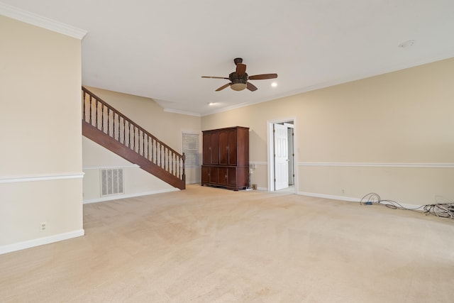 unfurnished living room with visible vents, ornamental molding, ceiling fan, stairway, and light colored carpet