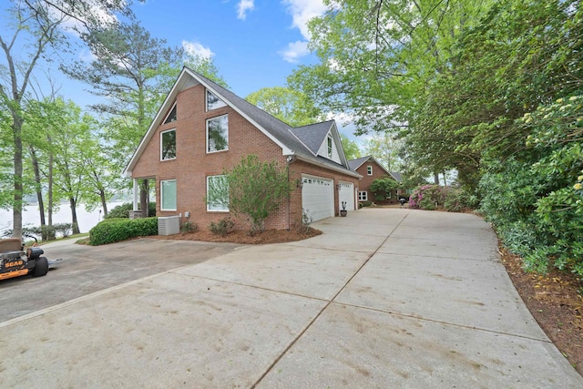 view of side of home with concrete driveway, brick siding, and central AC
