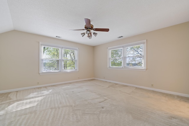 spare room with visible vents, light carpet, and a wealth of natural light