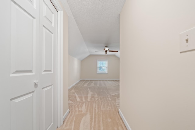 bonus room with a ceiling fan, a textured ceiling, light colored carpet, vaulted ceiling, and baseboards