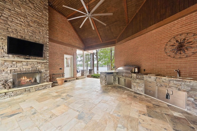view of patio / terrace featuring exterior kitchen, ceiling fan, an outdoor stone fireplace, a sink, and a grill