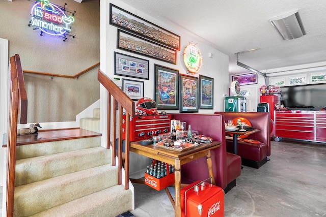 game room with a textured wall, concrete floors, and a textured ceiling