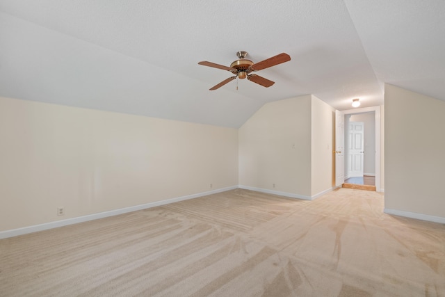 additional living space featuring baseboards, light carpet, a ceiling fan, and lofted ceiling