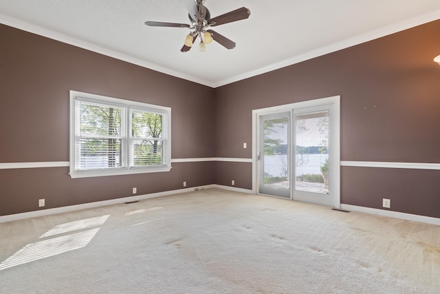 carpeted spare room with crown molding, baseboards, visible vents, and ceiling fan