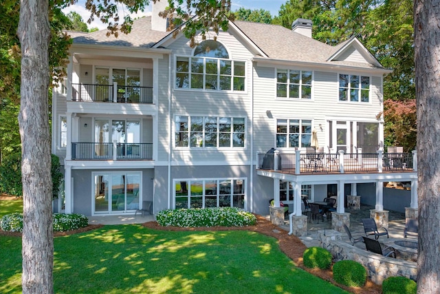 back of house featuring a balcony, a patio area, and a lawn