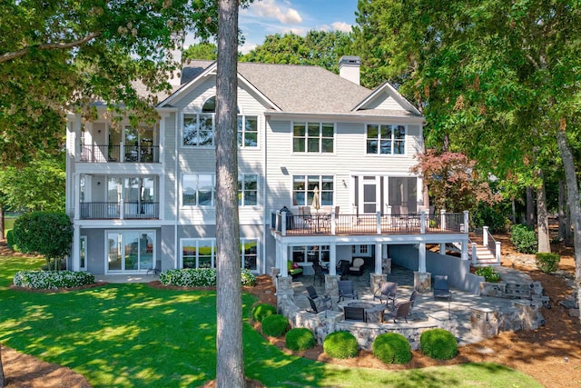 rear view of house with a balcony, an outdoor living space, a patio, and a lawn