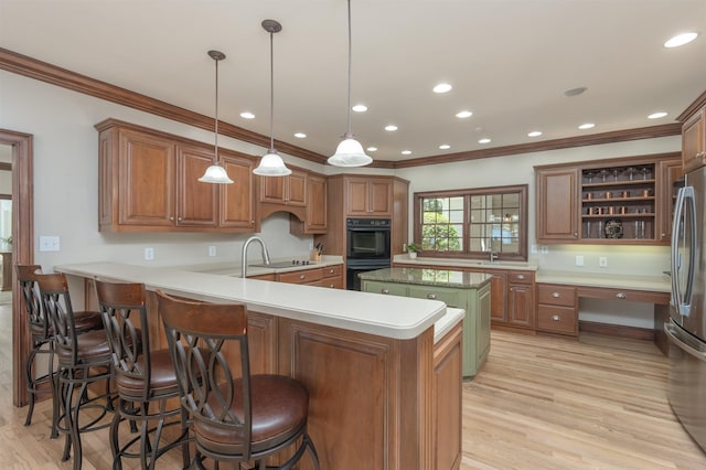 kitchen featuring built in desk, kitchen peninsula, pendant lighting, light hardwood / wood-style floors, and black appliances