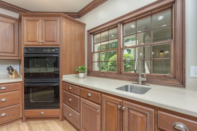 kitchen featuring crown molding, sink, double oven, and light hardwood / wood-style flooring