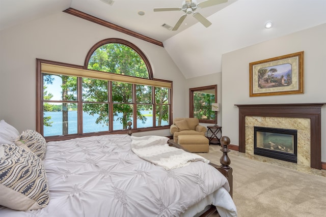 carpeted bedroom featuring ceiling fan, a water view, lofted ceiling, and a fireplace