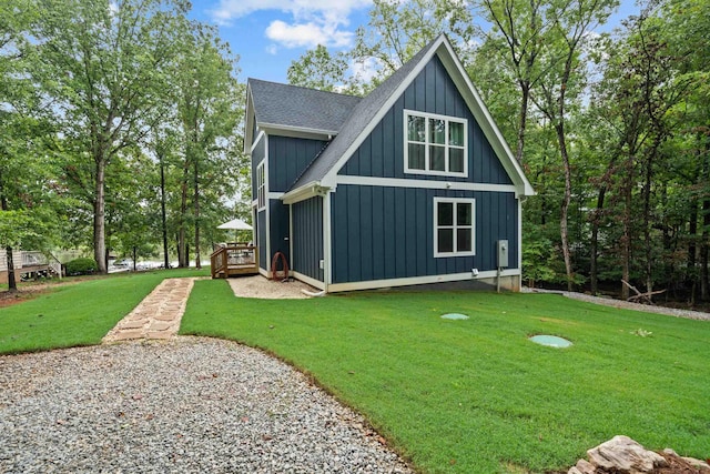 back of house featuring board and batten siding, a yard, a shingled roof, and a deck